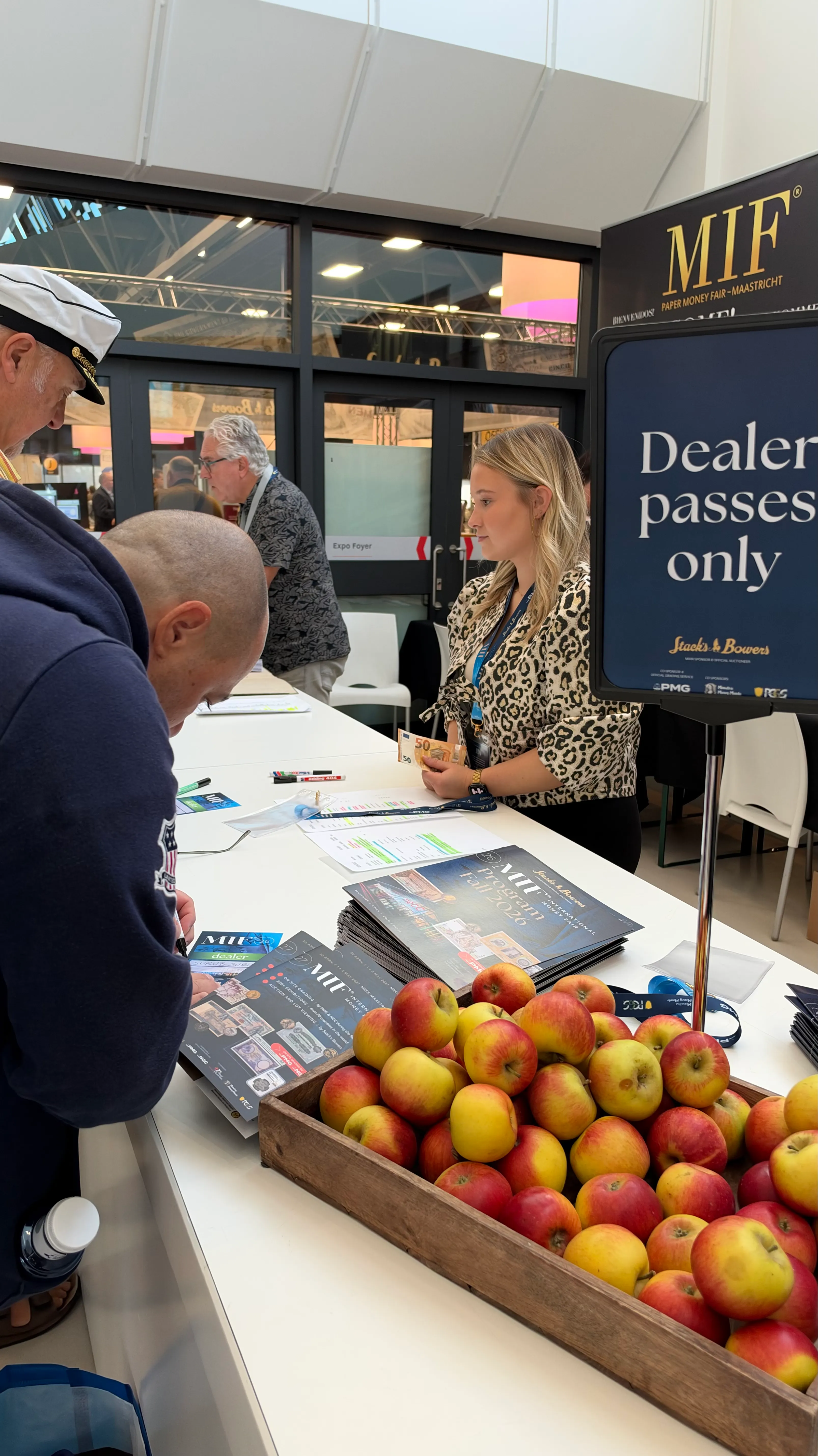 Registration desk with printed programs and a crate of apples