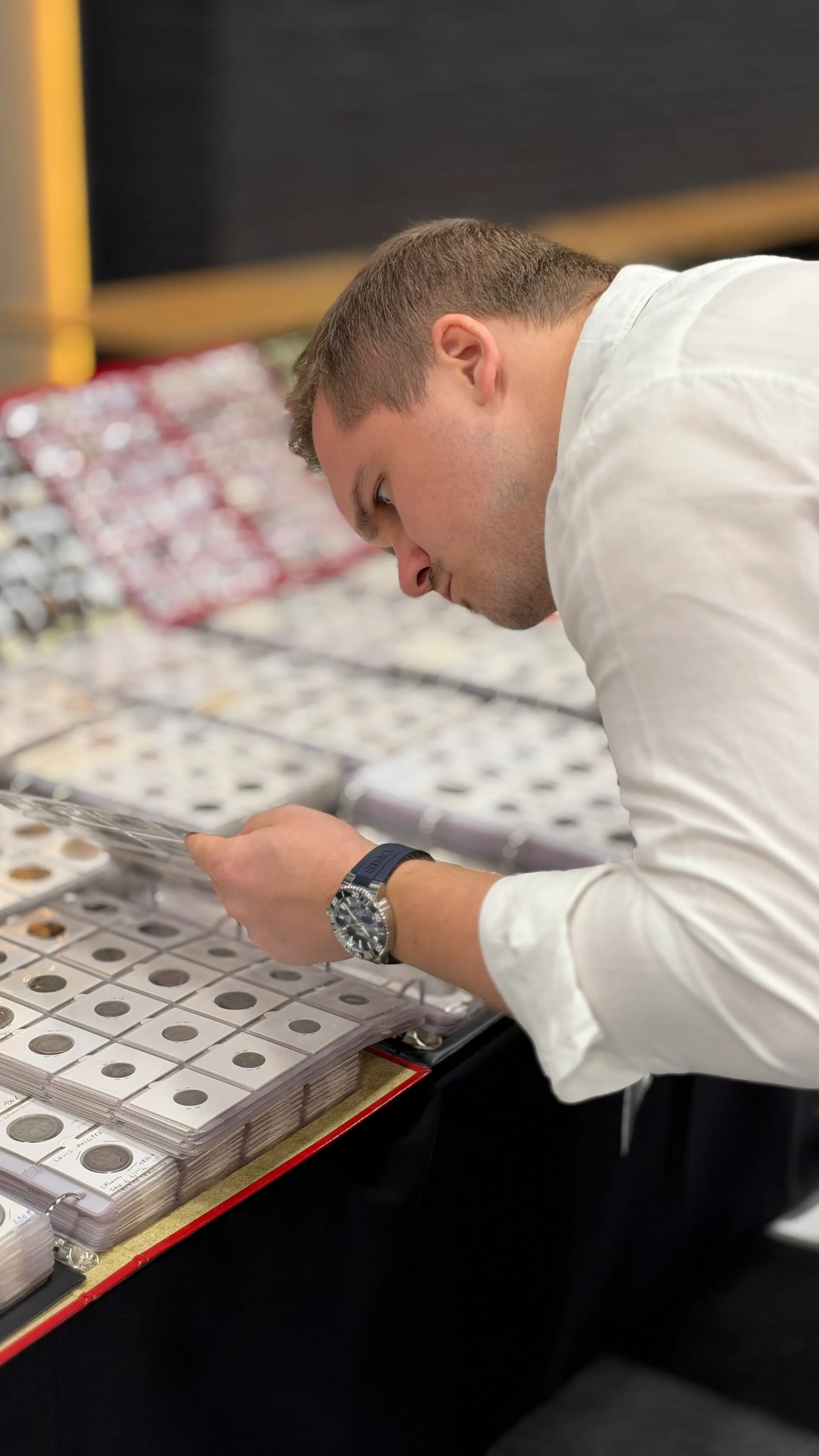 Visitor leaning over trays of coins in cardboard holders