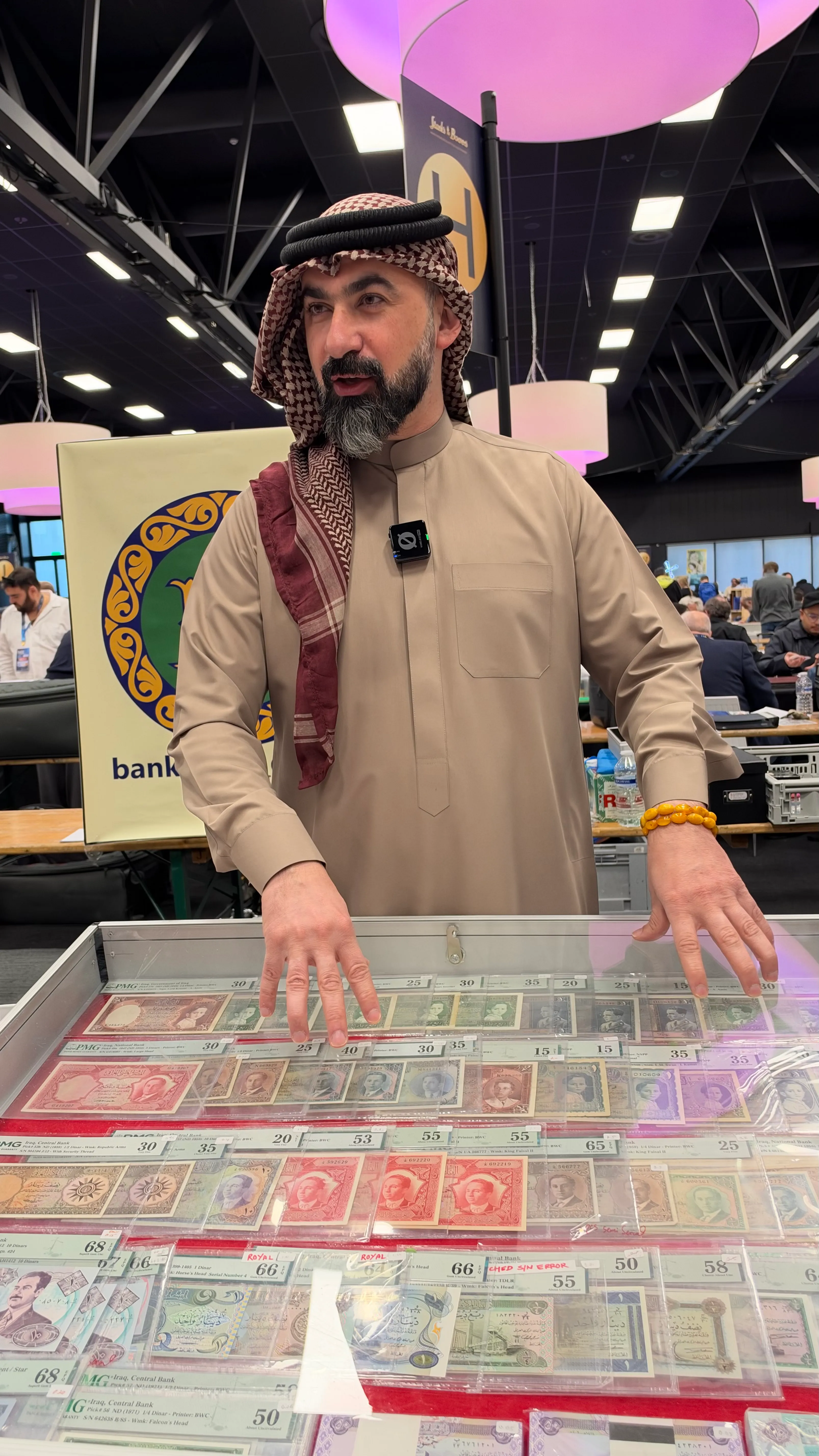 Dealer presenting graded Iraqi banknotes in a display case
