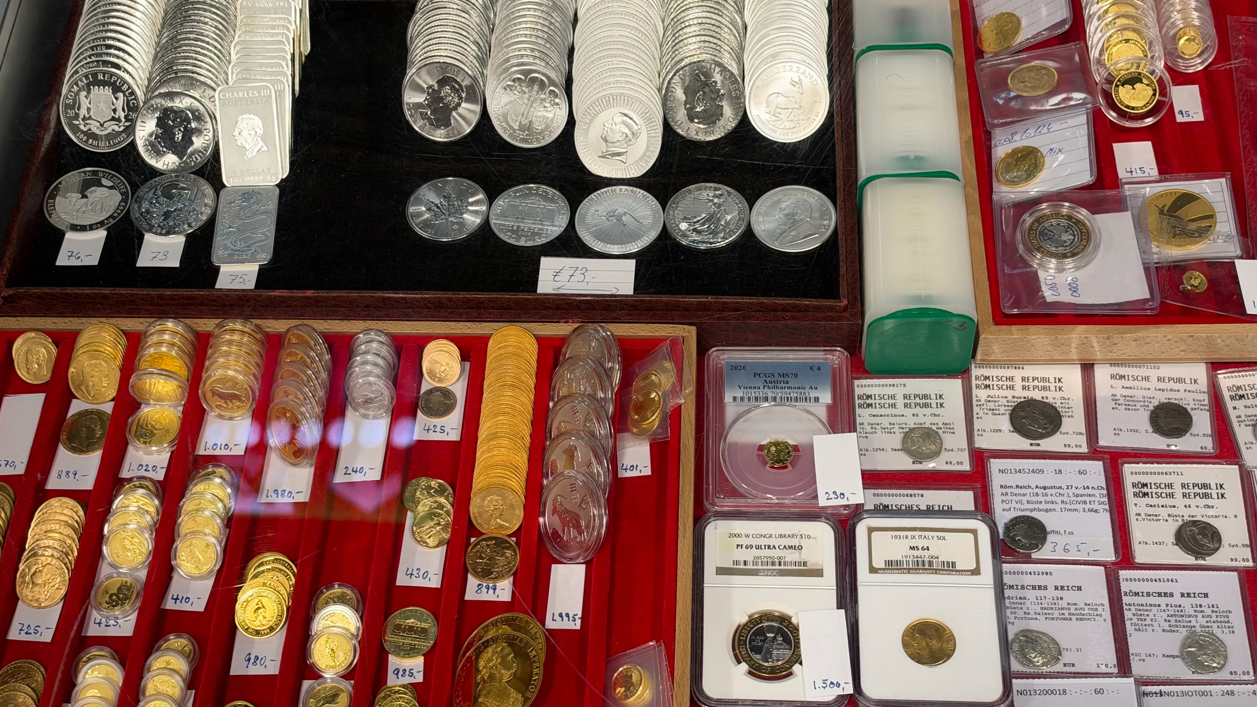 Display of silver and gold bullion coins, graded coin slabs and Roman silver coins