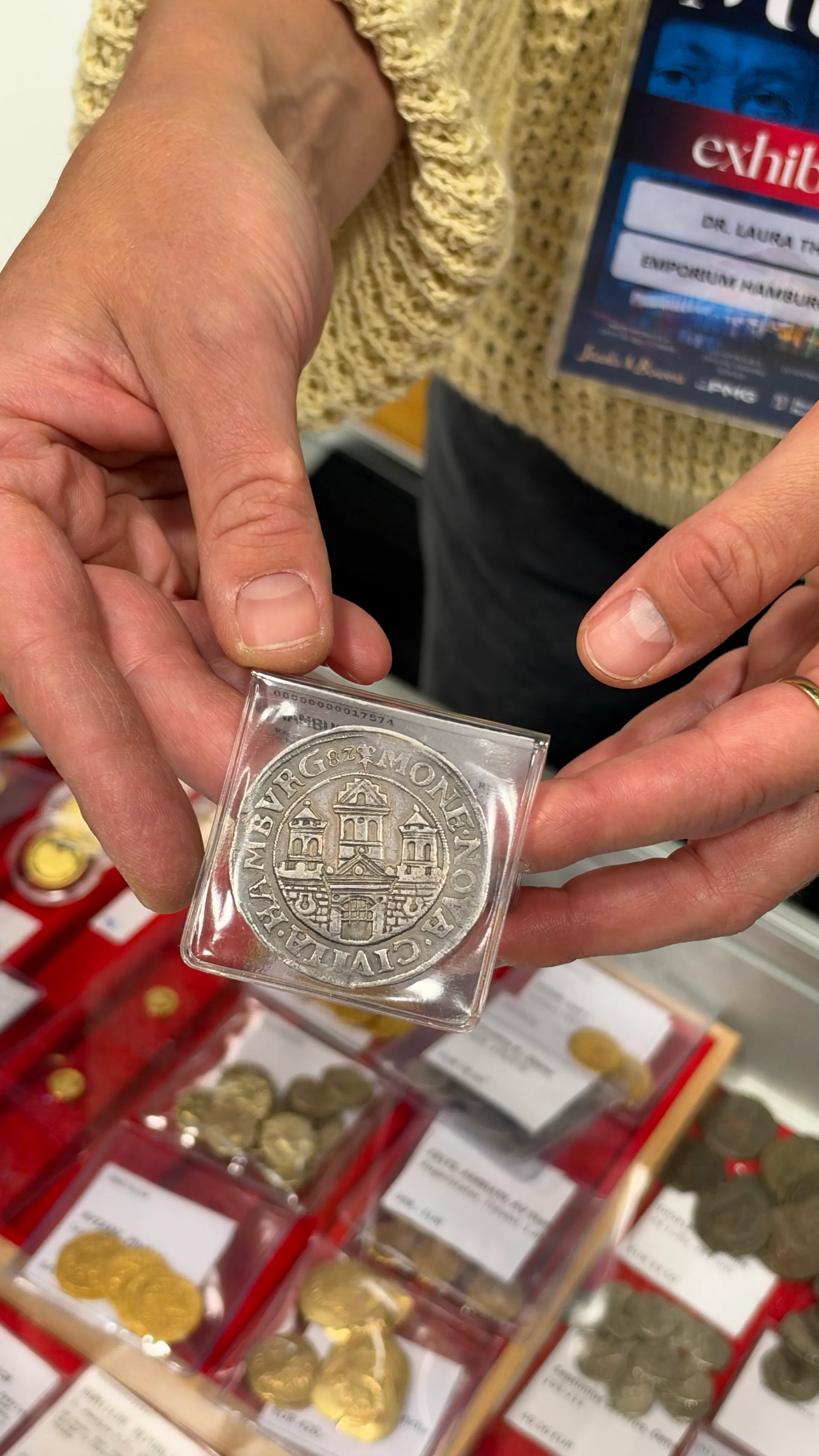 Exhibitor holding a silver coin of Hamburg in a protective flip